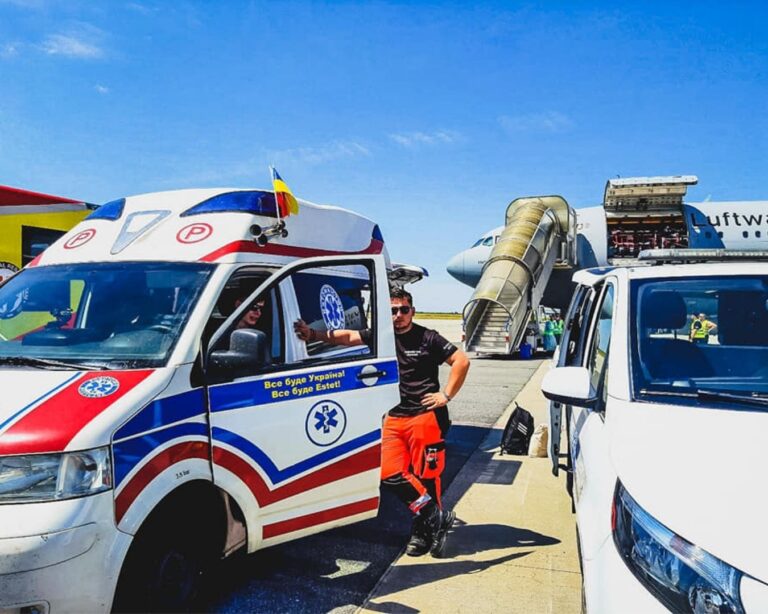 Ratownik przy ambulansie na płycie lotniska, w tle samolot