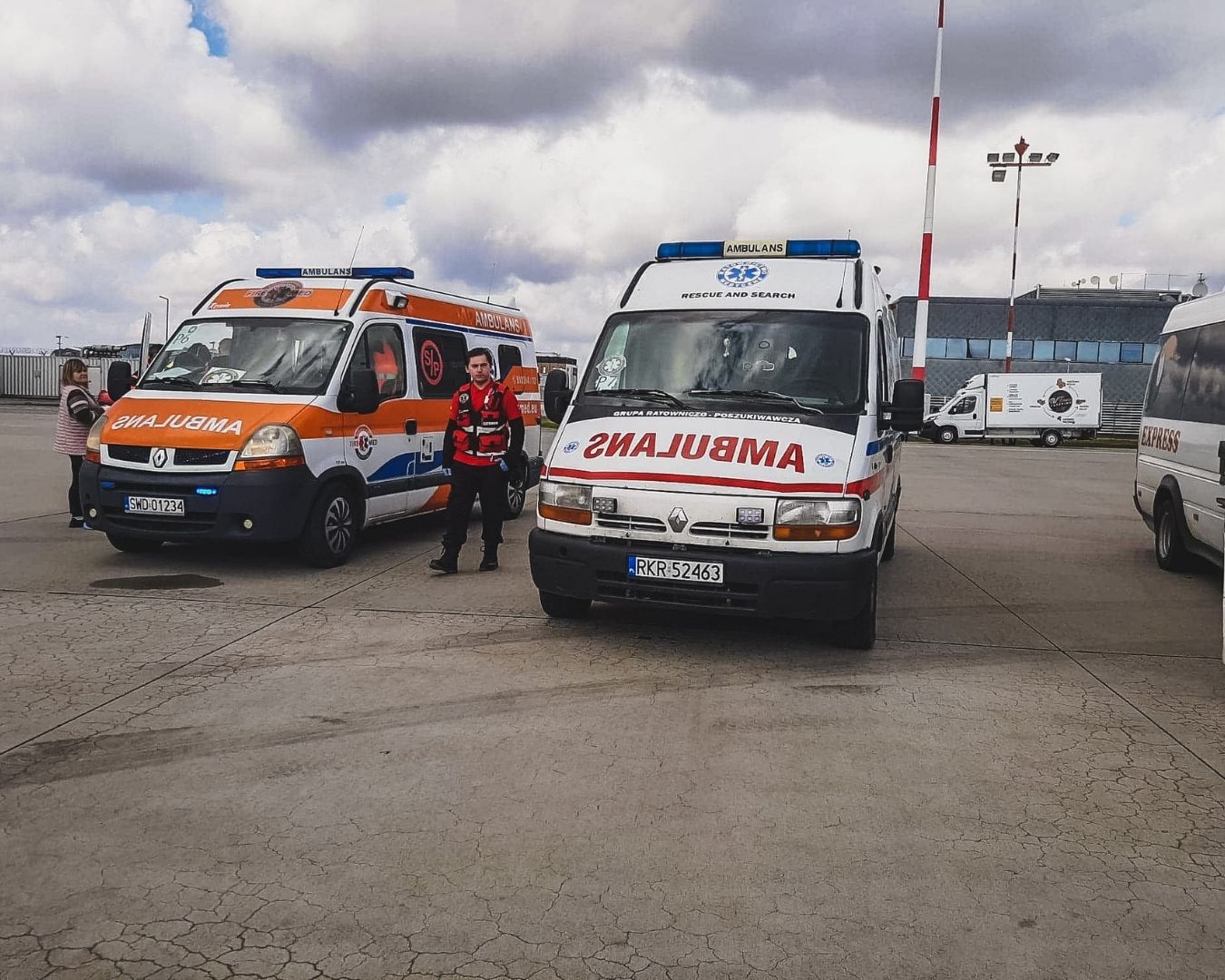 Ewakuacje medyczne: ratownik przy dwóch ambulansach na płycie lotniska