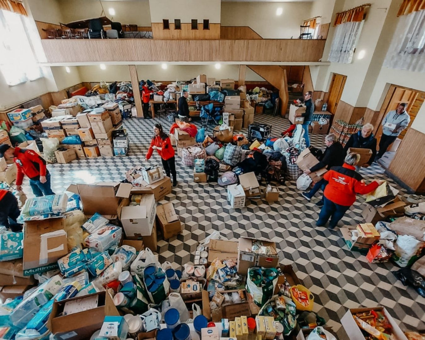 Magazyn pomocy humanitarnej: widok z góry na salę wypełnioną kartonami z darami i pracujących wolontariuszy