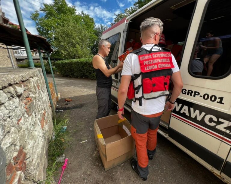Ratownicy wyładowują kartony z darami z samochodu