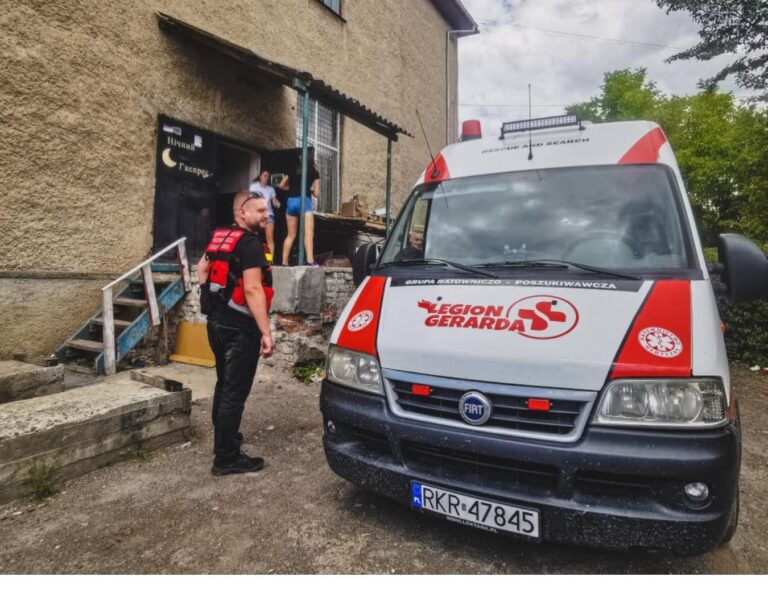 Ambulans Legionu Gerarda przed budynkiem, do którego przekazywana jest pomoc
