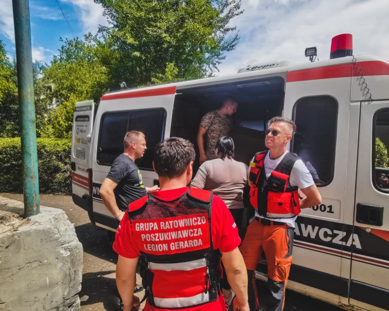 Misje humanitarne: ratownicy i odbiorcy pomocy przy otwartym samochodzie z darami